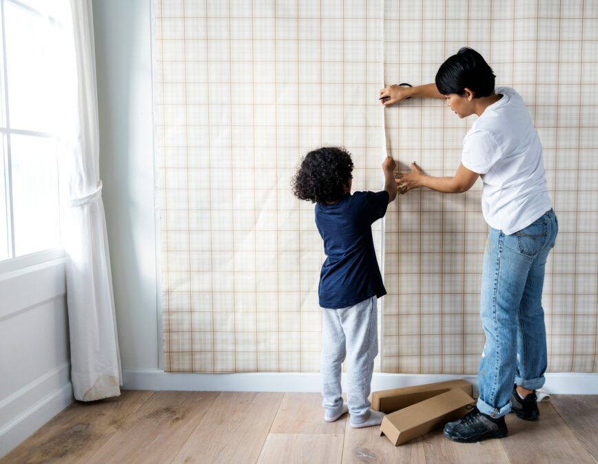 Child helping parent put up wallpaper